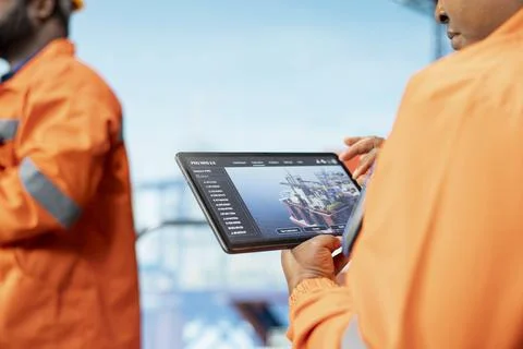 Close up of offshore platform experts using tablet app to monitor equipment 写真素材