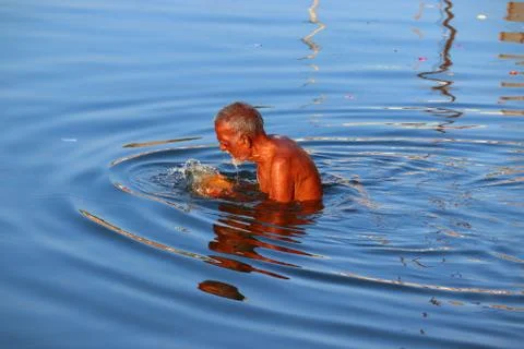 Close-up of a old aged man bathing in the holy ganga river with blue clear wa Stock Photos