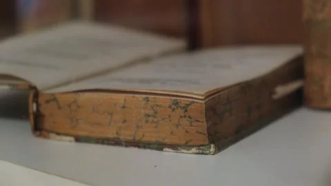 Close-up of an old antique book lying open on a white surface with marbled page Video stock 306656977