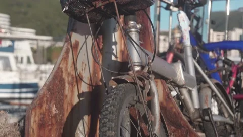 A close-up of an old bicycle, rusted with time, is tied to a metal pole. The Stock Footage 220461672