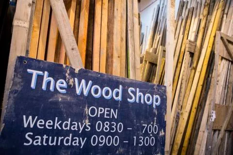 Close up of old blue Open sign for Wood Shop leaning against a stack of wooden Stock Photos