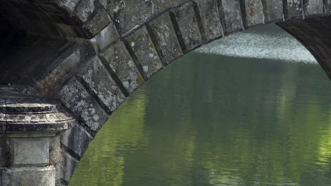 Close up of old bridge arc with river reflecting trees, Portugal Stock Footage 128967010