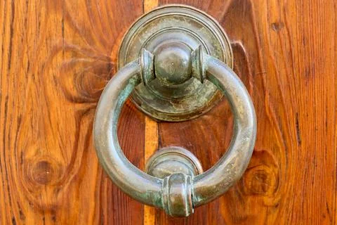 Close-up of an old circular door knocker hanging on a wooden door, showing th Stock Photos