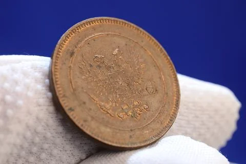 A close-up of an old coin held between fingers, featuring intricate designs.. Stock Photos