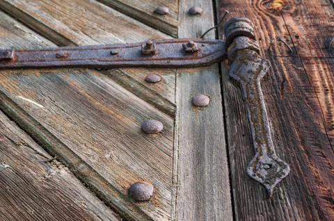 Close-up of an old, corroded and rusty hinge holding the wooden door. Stock Photos