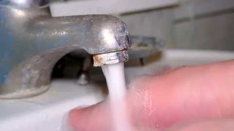 Close-up of old corroded faucet from which water flows. Hand washing. Stockbeeldmateriaal 218097758