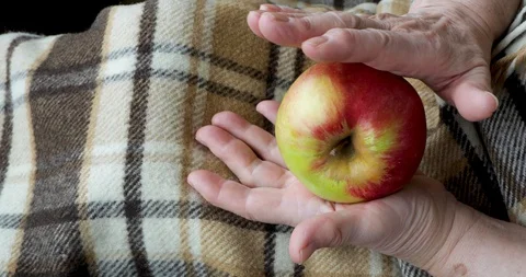 Close-up of an old female hands playing wih an apple Stock Footage 128657538