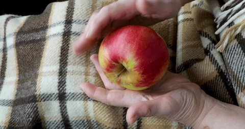 Close-up of an old female hands playing wih an apple Stock Footage 128657550