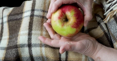 Close-up of an old female hands playing wih an apple Stock Footage 128657563