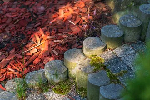 Close-up of an old garden path made of moss-covered stones with a sunbeam Stock Photos