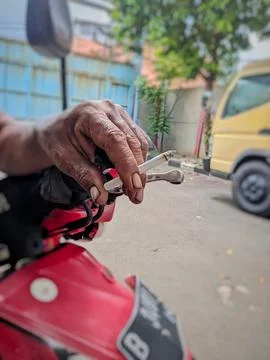 Close-up of Old Hand Holding Cigarette While on Motorcycle Handlebar Stock Photos