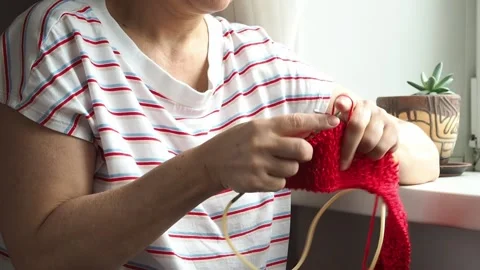 Close-up old hands knit a red woolen scarf by the window Stock Footage 169826661