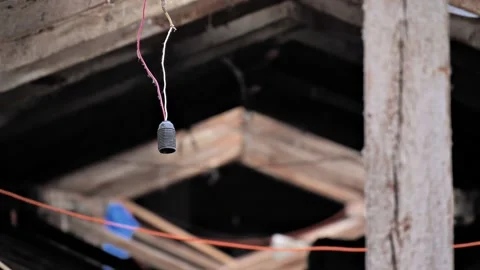 Close-up of an old light bulb socket hanging on a wire in an abandoned attic Stock Footage 212116884