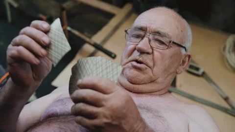 Close-up of old man with bare torso playing cards in the village Stockbeeldmateriaal 134421402