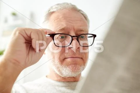 Close up of old man in glasses reading newspaper Stock Photos