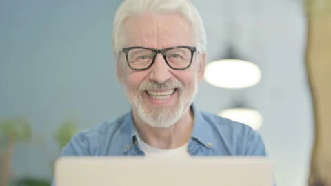 Close Up of Old Man Smiling at Camera while using Laptop Stock Footage 230538658
