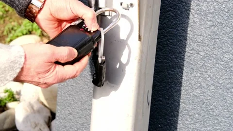 Close-up of an old man's hand opening a combination lock on a street post, co Stock Footage 154135041
