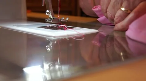 Close up old married womans hands at sewing machine with pink fabric Stock Footage 43666289