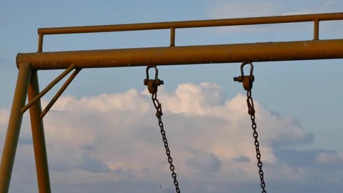 Close-up old nostalgic swing set structure rusty chains hanging under cloudy sky Stock Footage 318194392