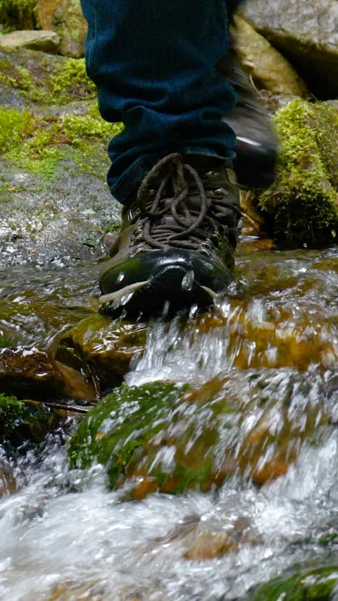 Close-up of an old pair of leather hiking boots belonging to a hiker crossing a 库存影片 334387198