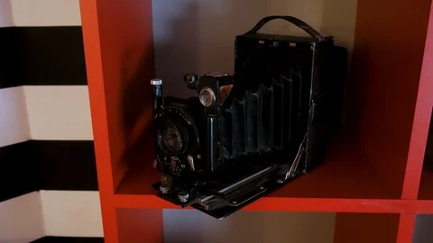 Close up of an old photo camera standing on red shelf. Stock. Vintage object Stock-Footage 129670878