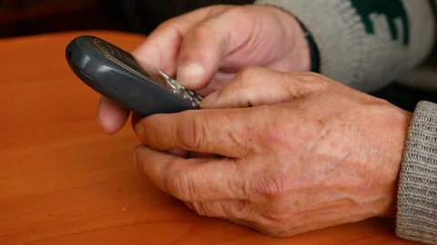 Close-up of an old push-button mobile phone in the hands of a pensioner. An elde 스톡 동영상 165481433