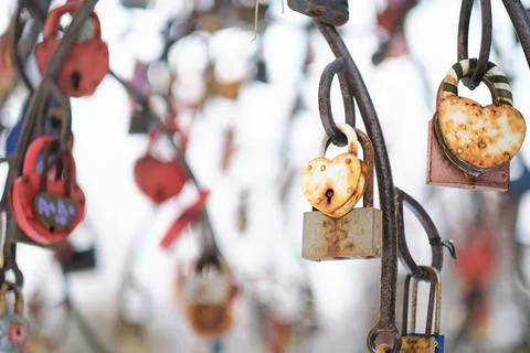 Close up old rusty locks heart shaped on wire rope. Love lock on the bridge 스톡 사진