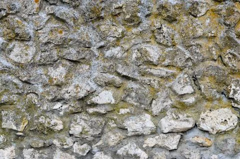 Close-up of  old rusty stone and concrete wall with yellow  moss on it. Stock Photos