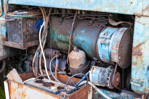 Close-up on an old rusty tractor or truck engine with a battery and oil drips Stock Photos