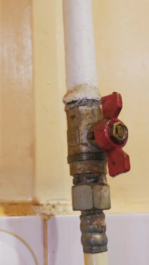 Close Up of Old Rusty Water Pipe with Red Shut Off Valve Against Yellow Wall Video stock 333167867