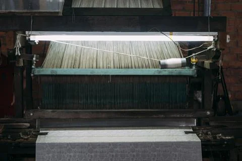 Close-up of old silk weaving machine running, creating silk cloth. Stock Photos
