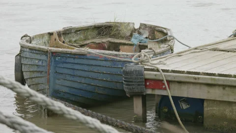 Close up of an old small blue clinker row boat tied to a jetty. 4K locked tripod Stock Footage 164650295