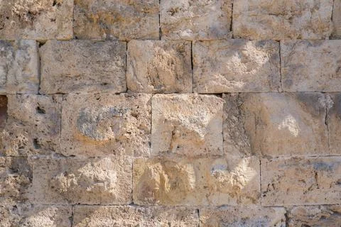Close-up of an old stone wall with weathered rectangular blocks in natural li Foto stock