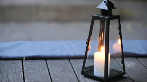 Close up of an old-style lantern with a burning candle inside on a wooden deck. Stock Footage 197531145