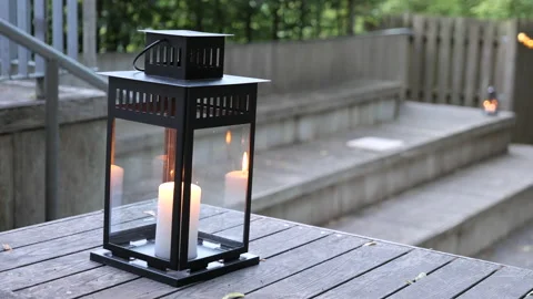 Close up of an old-style lantern with a burning candle inside on a wooden deck. Video stock 197531282