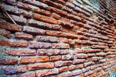A close up of an old, weathered brick wall with uneven, rough textured red .. Stock Photos