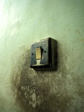 Close up of an old, weathered electrical switch on a wall with peeling pain.. Stock Photos