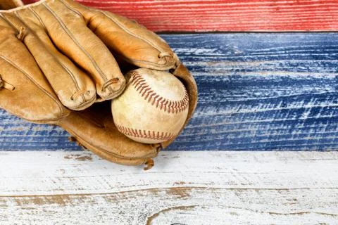 Close up of old worn baseball mitt and baseball on faded wooden boards painte Stock Photos