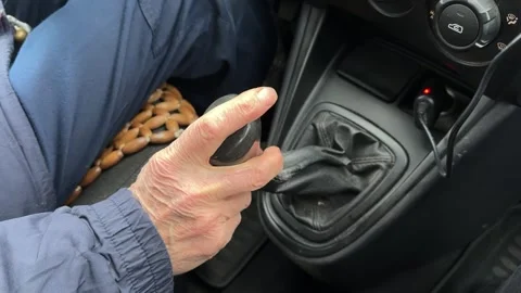 Close-up of an old wrinkled-skinned man's hand shifting gears on the lever of a Stock Footage 271231209