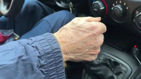 Close-up of an old wrinkled-skinned man's hand shifting gears on the lever of a Stock-Footage 271603158