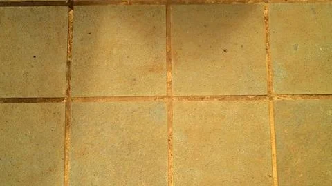 Close-up of old yellow tiled floor with grout lines Stock Photos