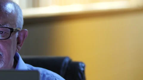 Close up of an older man's face as he looks at computer screen 스톡 동영상 54566291