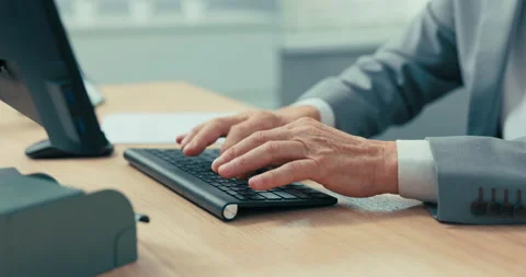 Close-up of older man's hands on black computer keyboard, businessman in gray Stock Footage 164868381