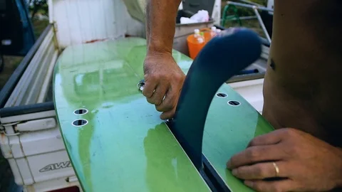 Close-Up of Older Surfer Fixing a Surfboard Fin Stock Footage