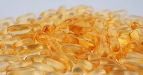 Close-up of omega 3 bright orange gel capsules rotate on white background Stock-Footage 126340011