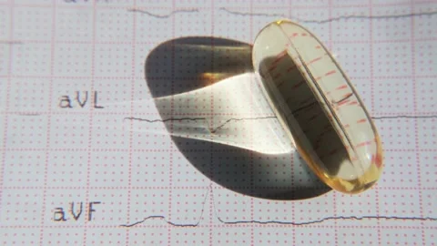 Close-up omega-3 capsule on ECG background. Healthy heart concept. Видео 201580465
