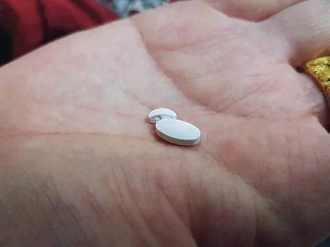 Close-up One and a Half White Medication Pills in a Palm of Hand Foto stock