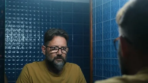 Close up of one sad depressed man looking himself in the mirror of the bathroom  Vídeo Stock 151322491