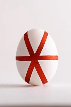 Close-up of one white Easter egg decorated with geometric red stripes on whit Stock Photos