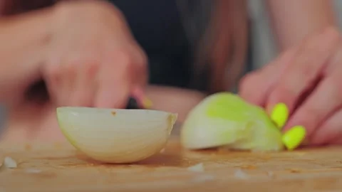 Close up onion half on cutting board woman slicing blurred background view Stock Footage 316135347